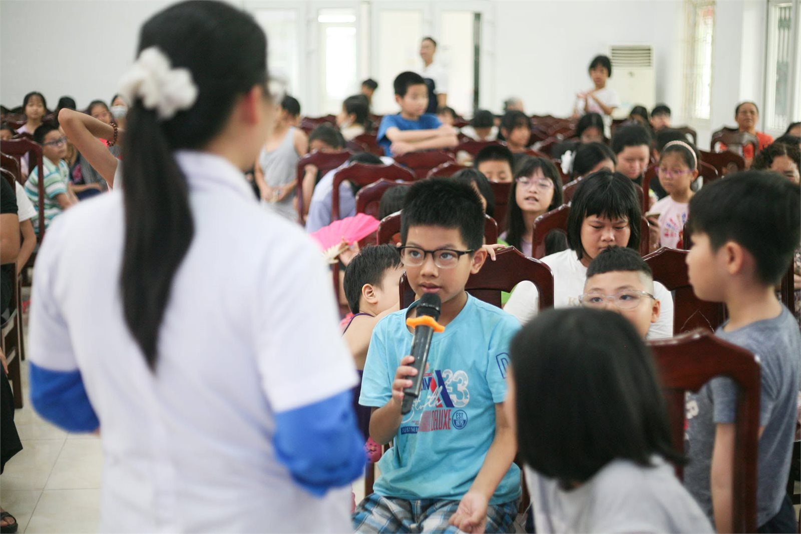 Một em thiếu nhi cầm micro đặt câu hỏi tại buổi tập huấn sơ cứu ở phường Mai Dịch